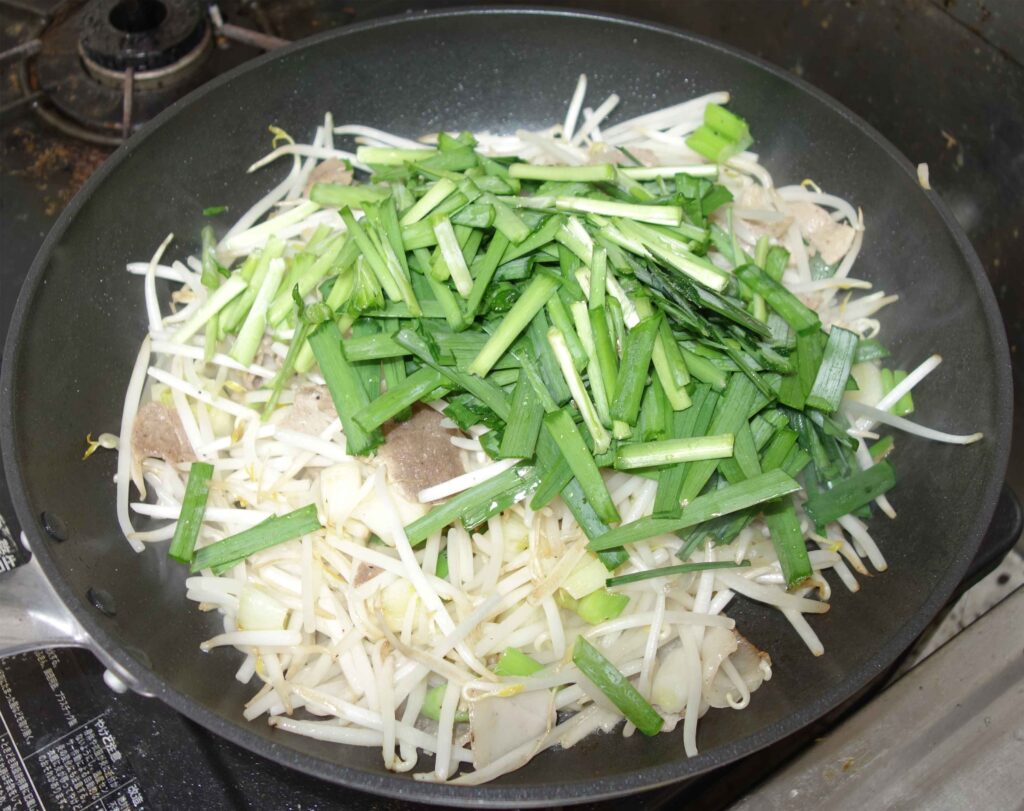 フライパンで調理中のニラともやし炒め