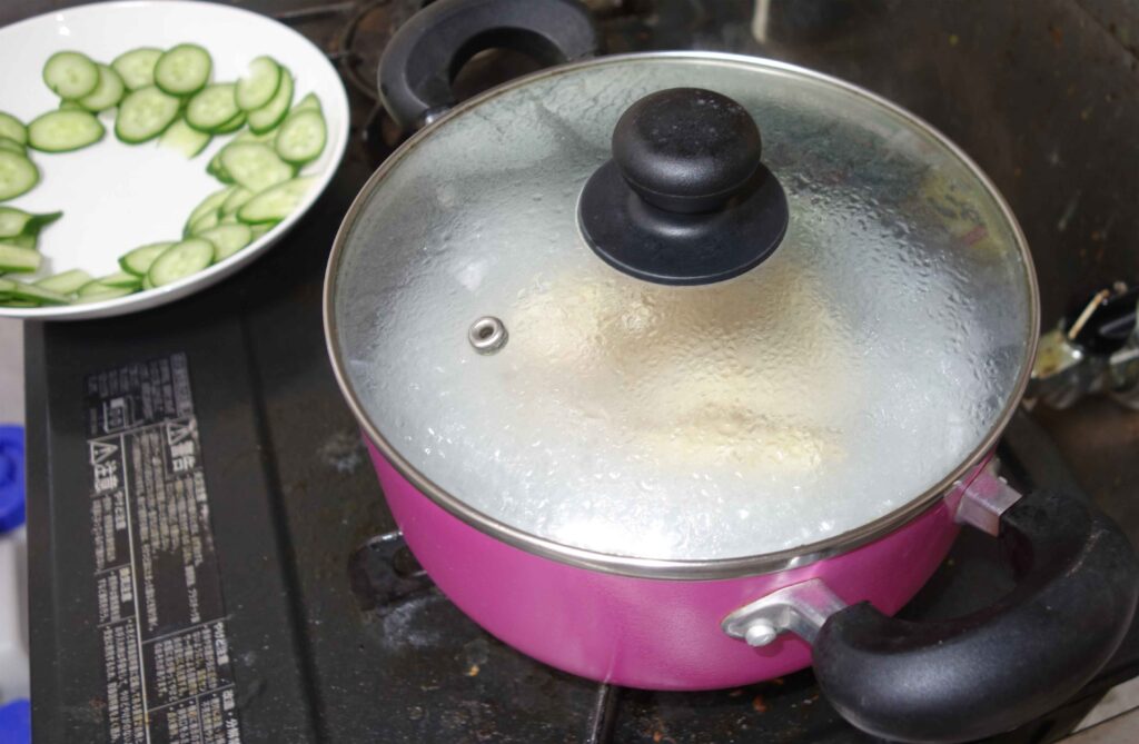 ピンク色の鍋で調理中とキュウリの皿