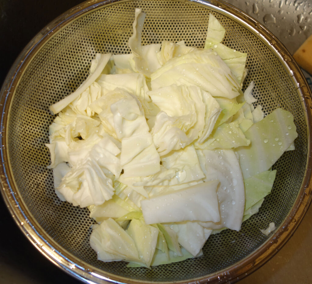 ザルに入った水洗いされたキャベツ