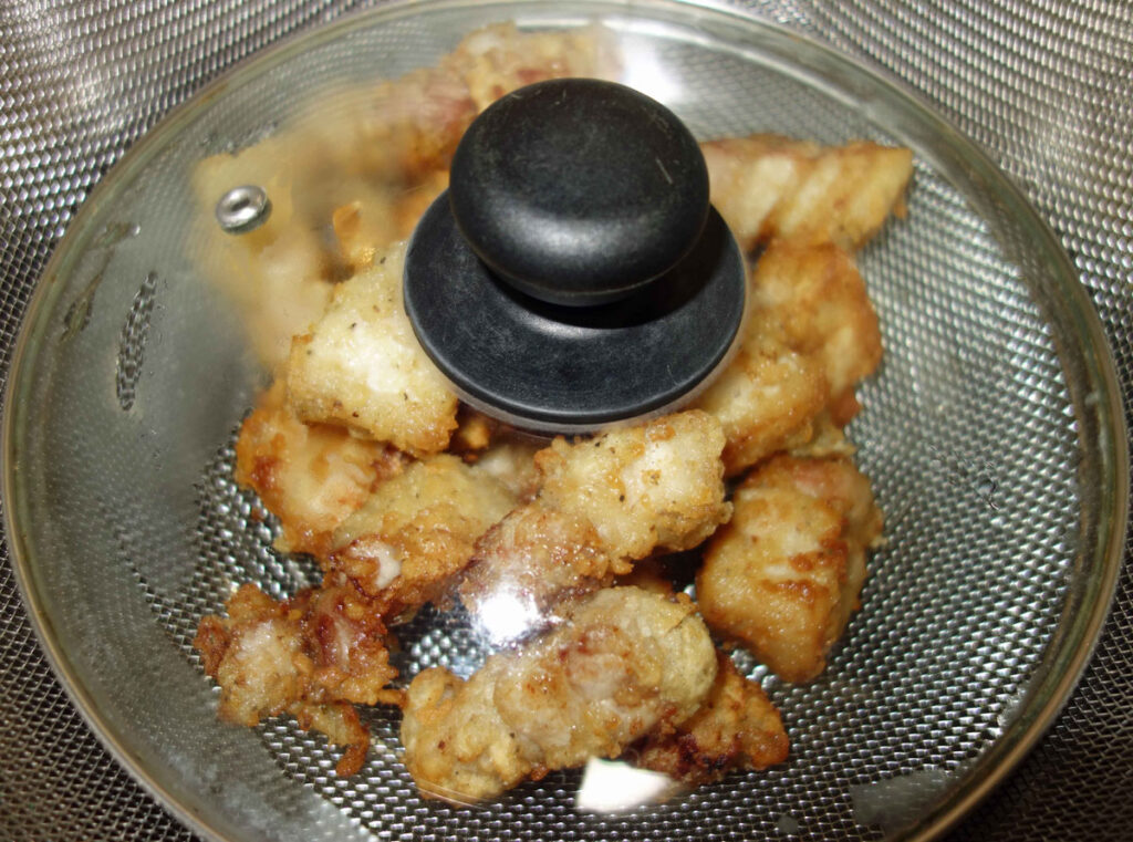 鶏肉の唐揚げが入ったザルと透明なフタ
