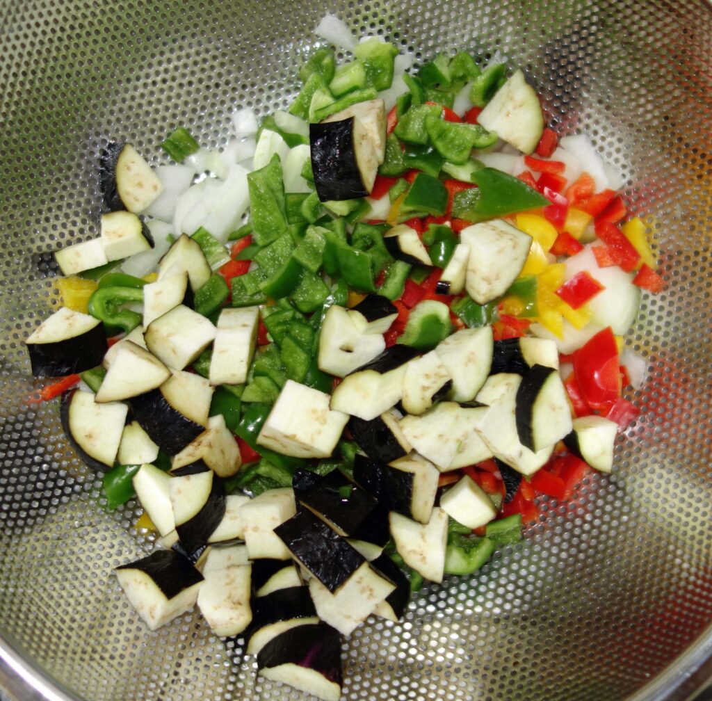ざるに入った角切りのナス、玉ねぎ、ピーマン