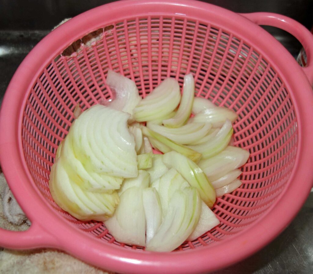 ピンク色のざるに入ったスライスされた玉ねぎ