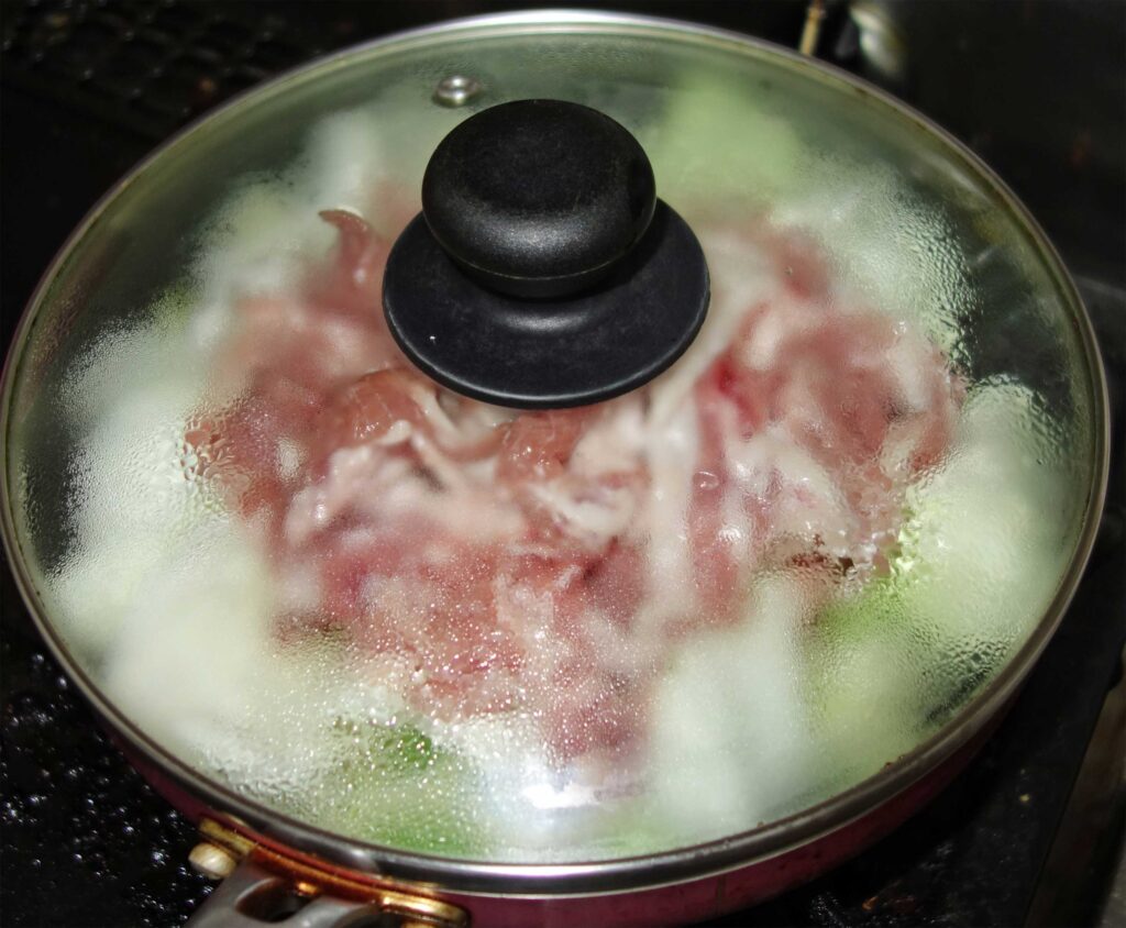 豚肉とキャベツを鍋で蒸している様子