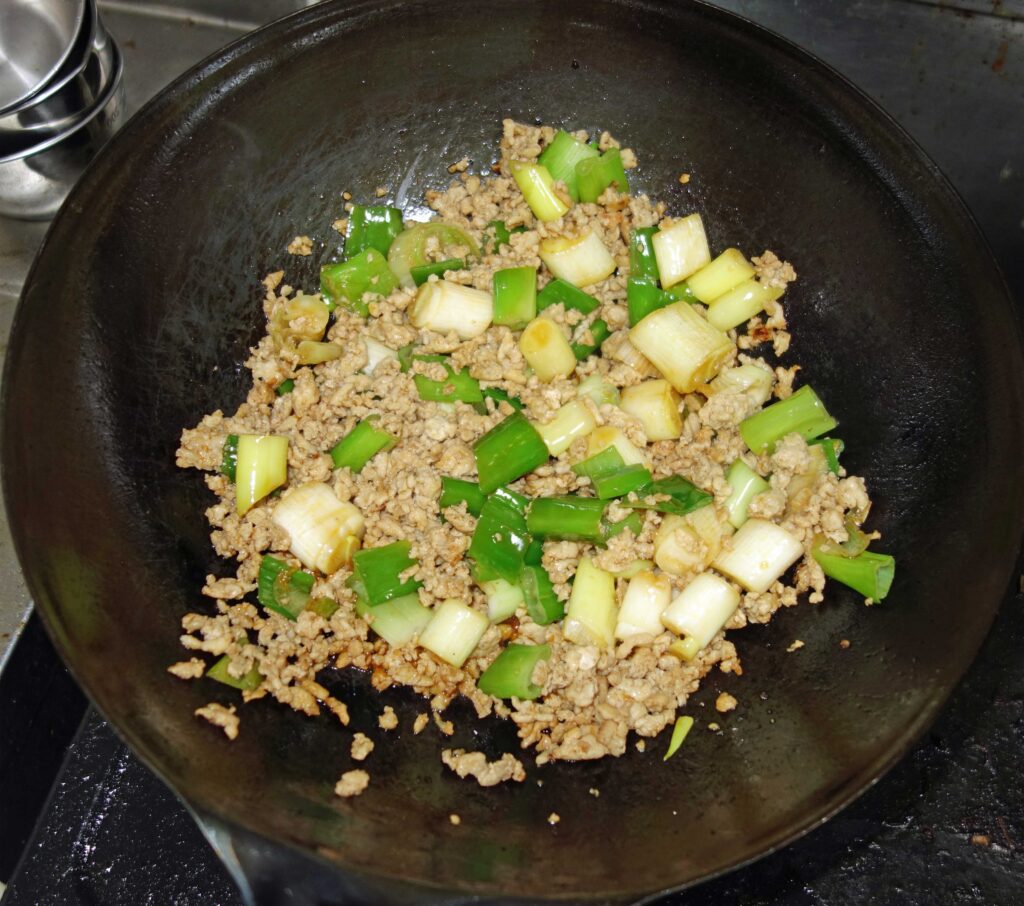 中華鍋で炒めたひき肉とネギ