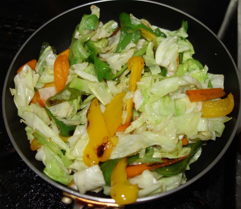 フライパンで炒めたキャベツ、ピーマン、ニンジンの野菜炒め