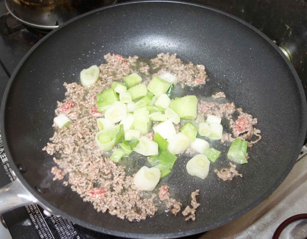 フライパンでひき肉とネギを炒めている様子