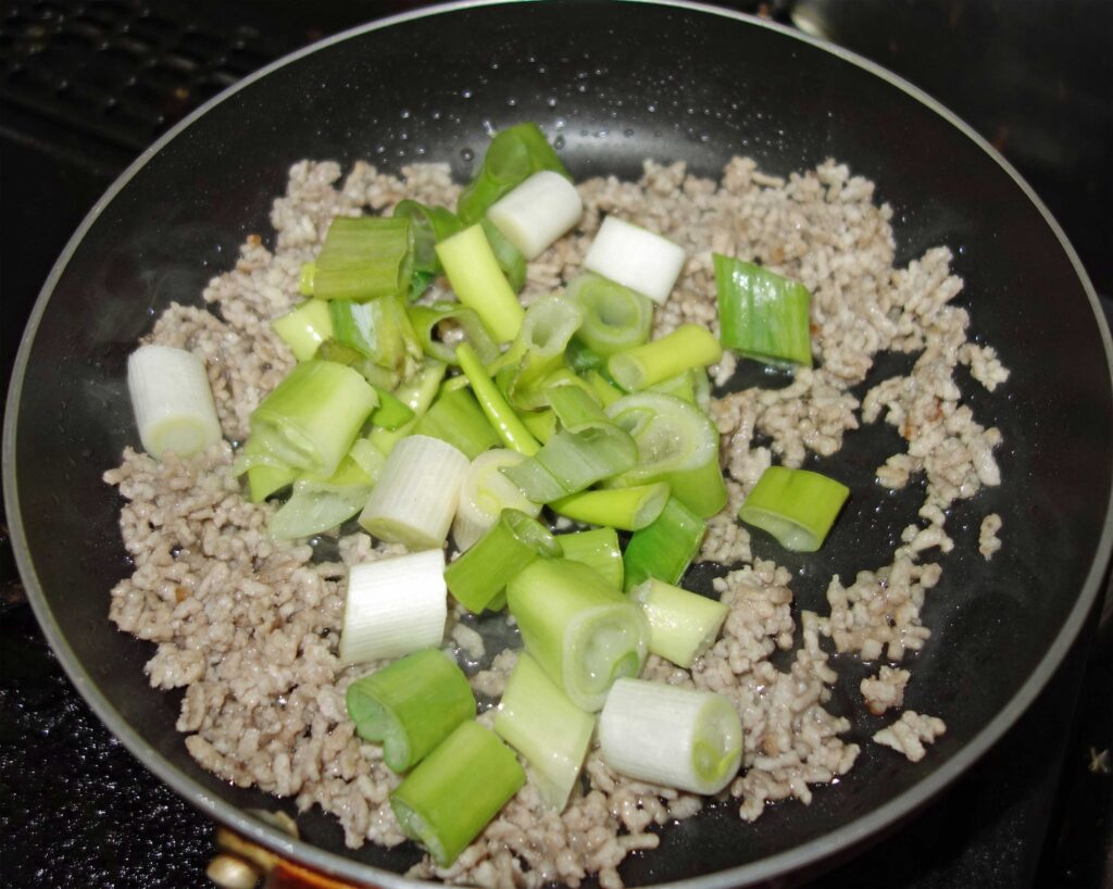 フライパンで鶏ひき肉とネギを炒めている様子