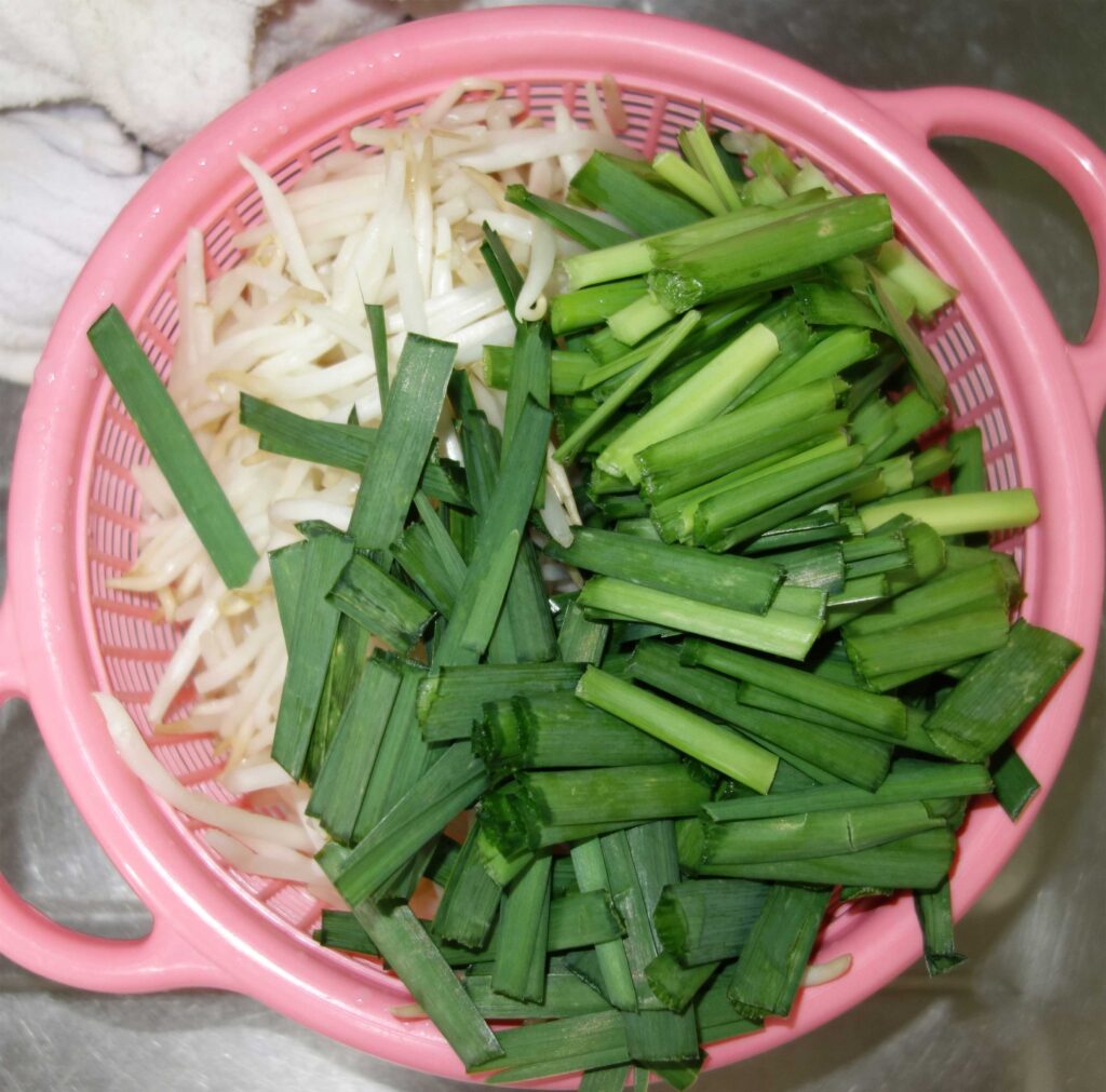 ピンク色のザルに入った切ったニラともやし