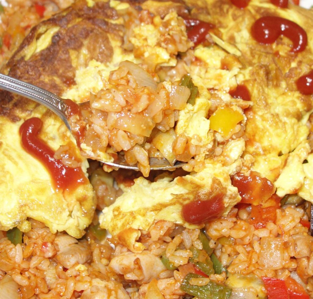 スプーンで持ち上げられたケチャップのかかったオムライス