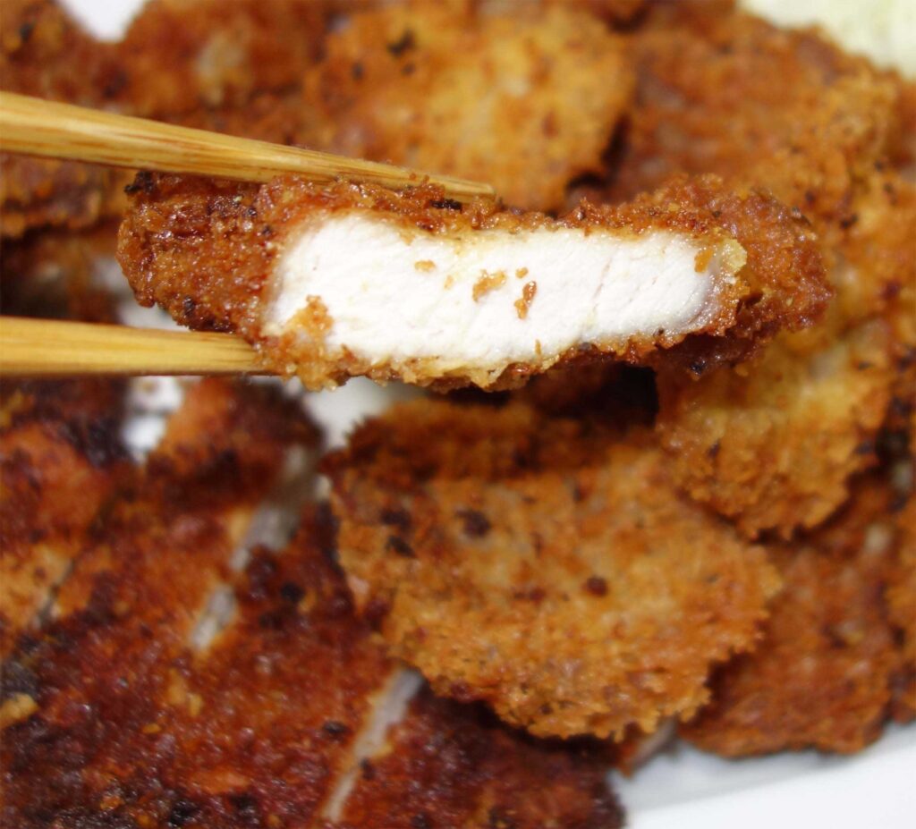 箸で持ち上げられた断面が見える豚カツ