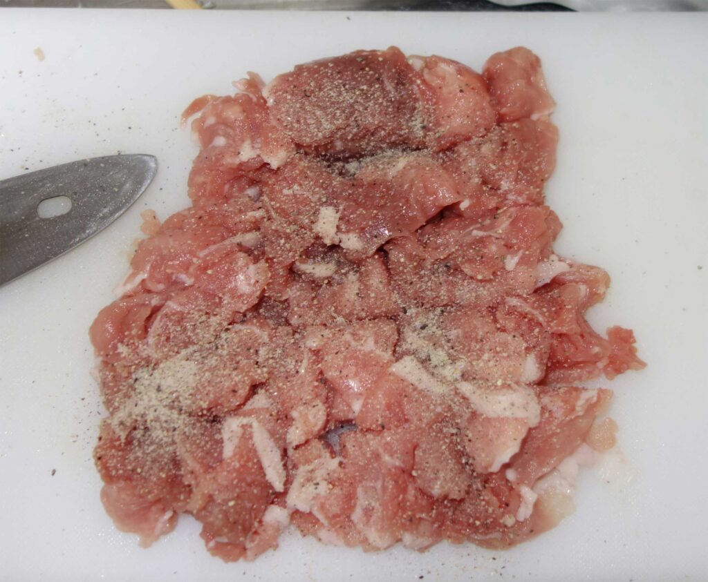 まな板の上の豚肉と塩コショウ
