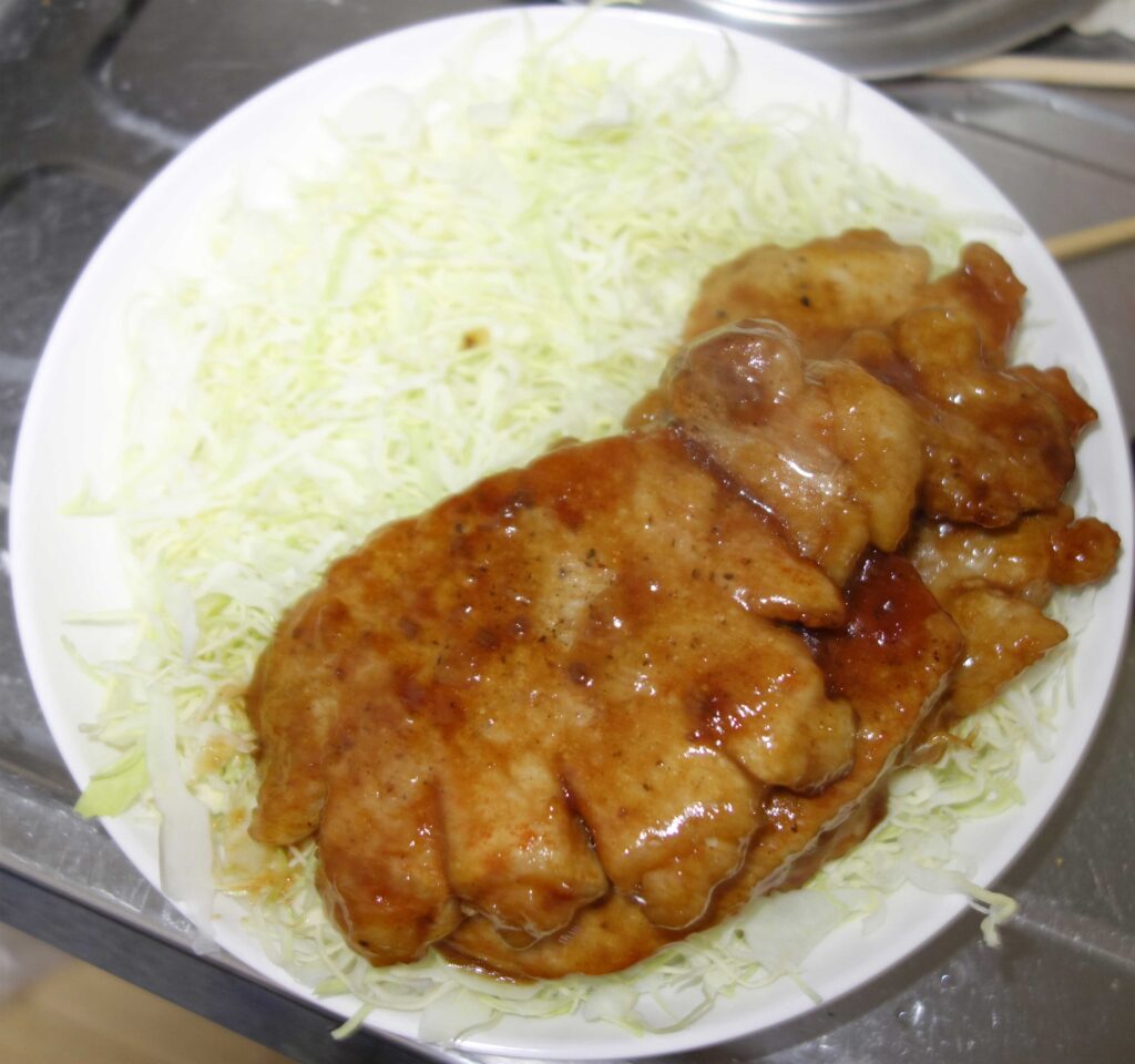 皿に盛られた豚の生姜焼きと千切りキャベツ