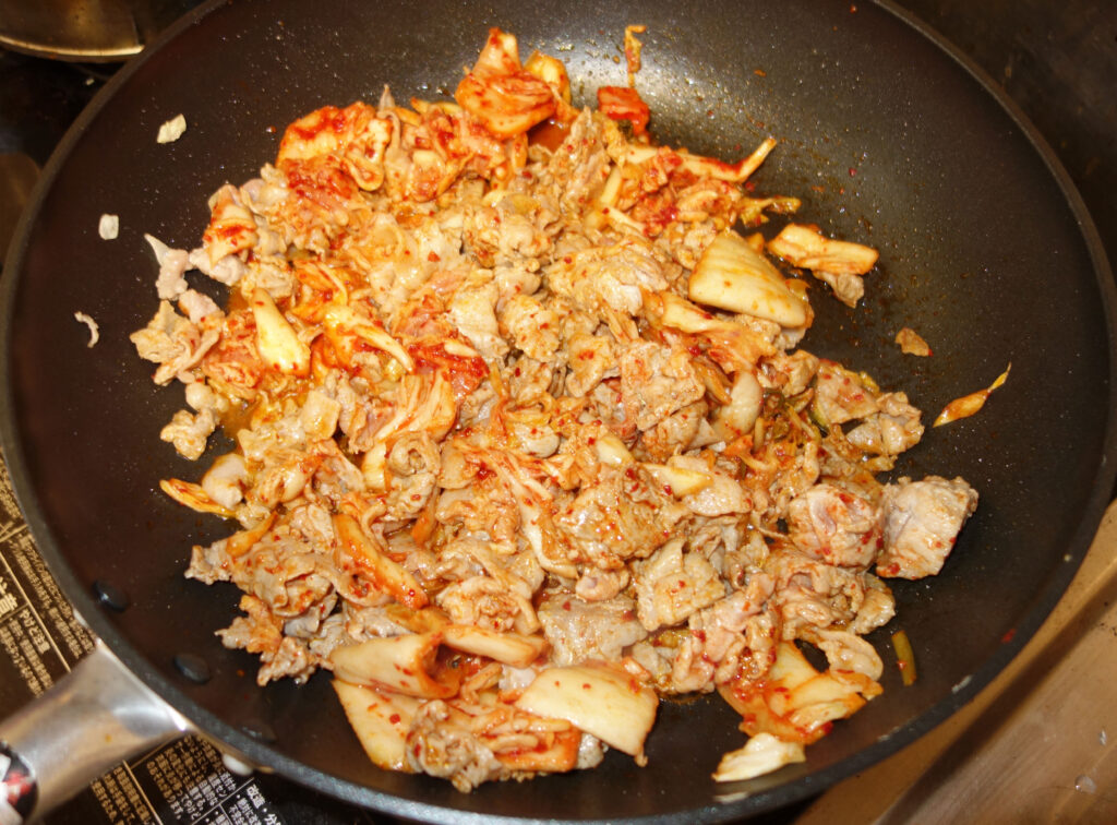 フライパンで炒めた豚肉とキムチ