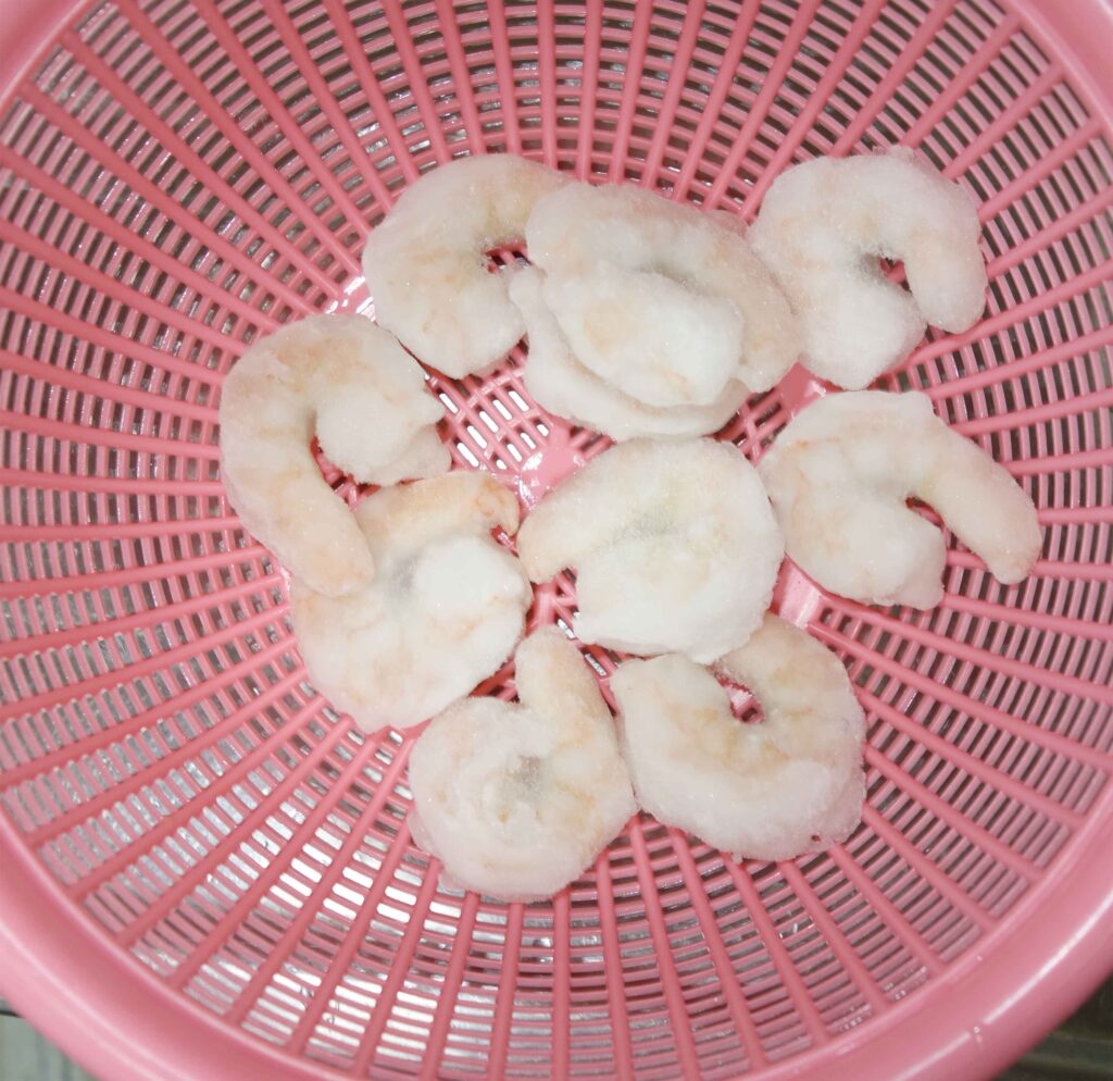 ピンク色のざるに入った冷凍エビ