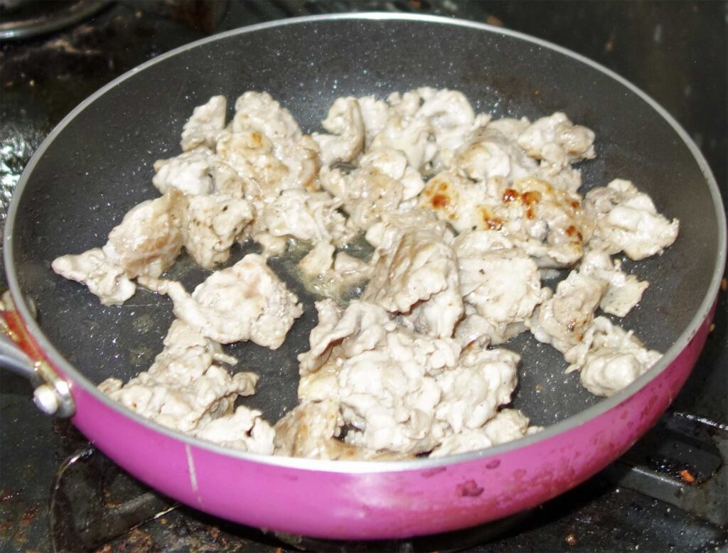 ピンク色のフライパンで炒めた肉