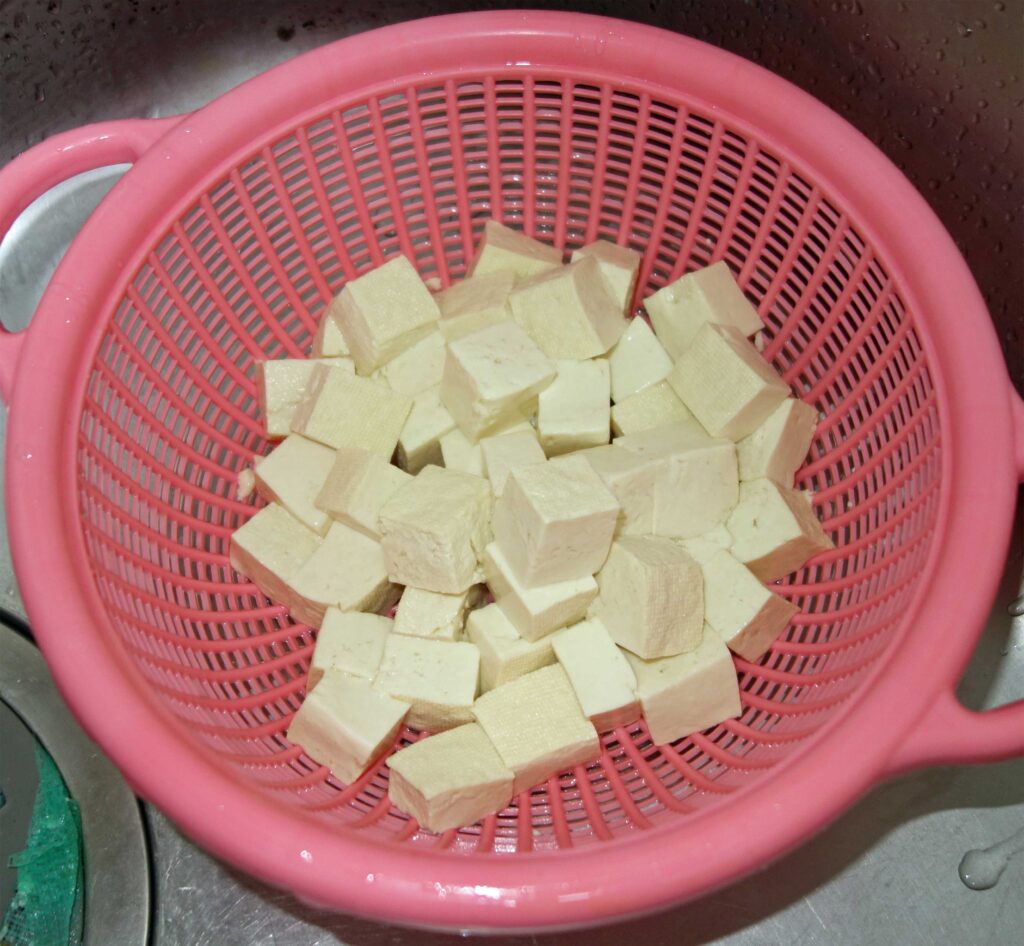 ピンク色のザルに入ったさいの目切りの豆腐