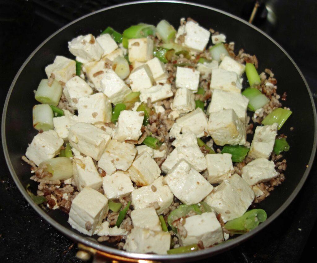 フライパンで豆腐とネギを炒めている様子