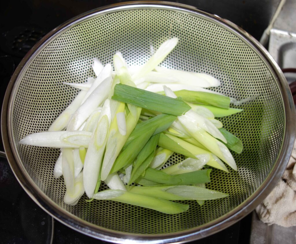 ざるに入った斜め切りのネギ