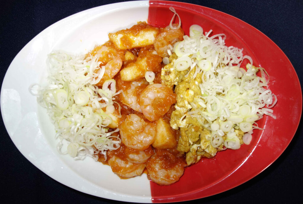 エビチリと卵料理と白髪ネギが紅白の皿に盛られた写真