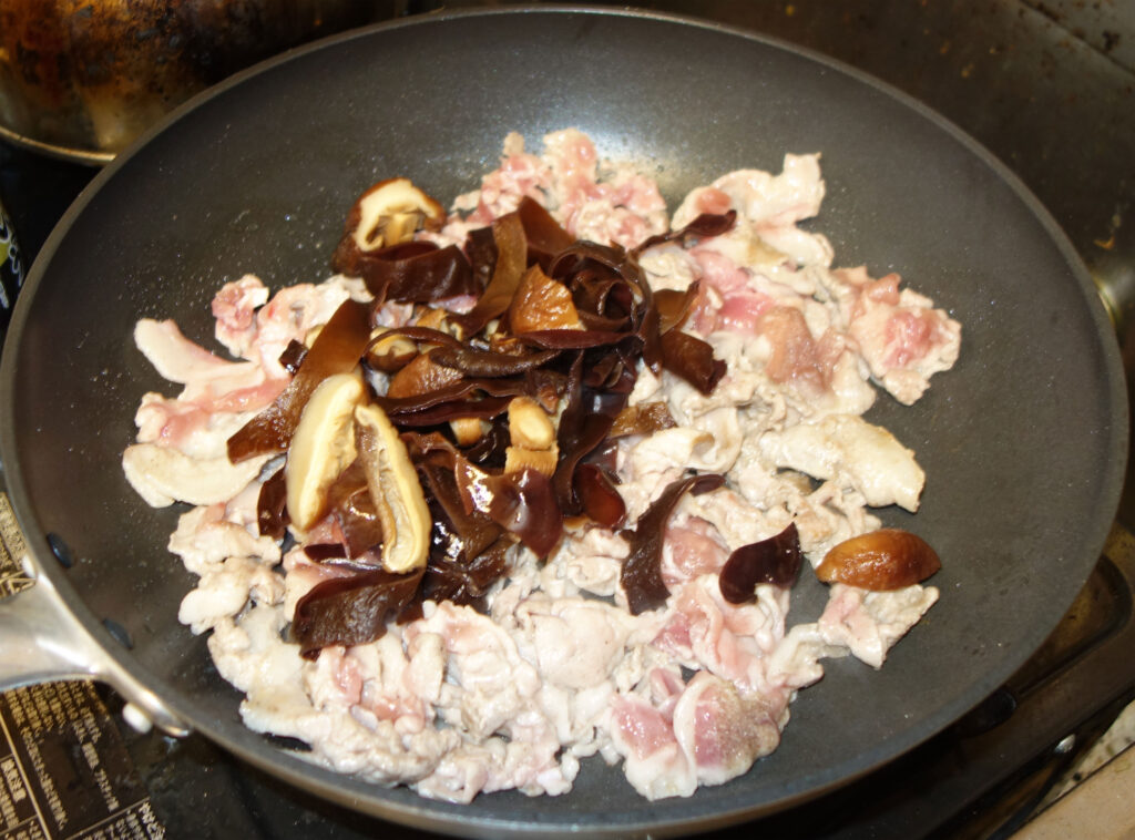 豚肉ときくらげとシイタケを炒めている様子
