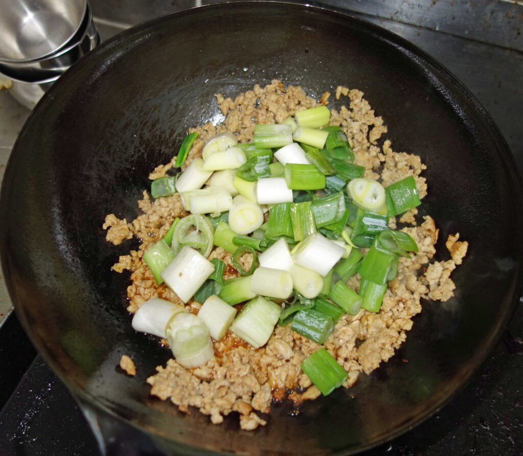 中華鍋でひき肉とネギを炒めている様子