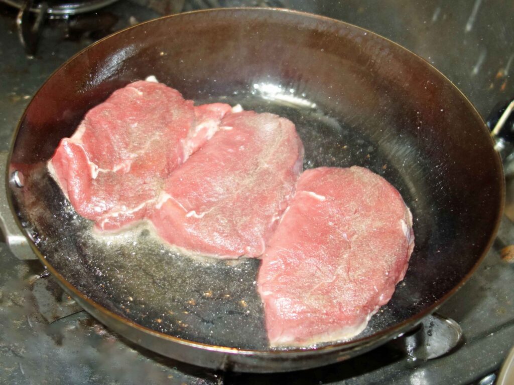 フライパンで焼かれる3枚の肉