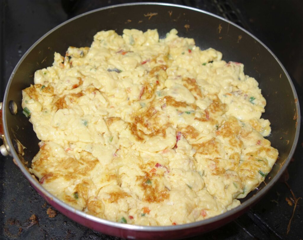 フライパンで調理された野菜入りスクランブルエッグ