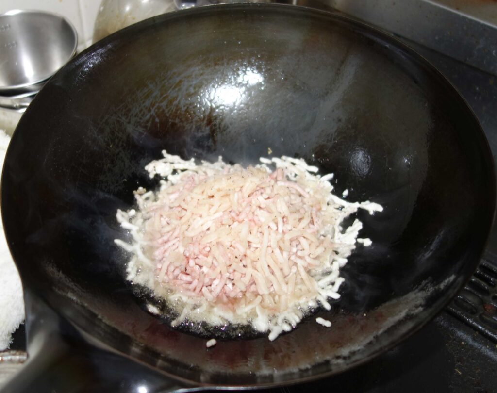 中華鍋でひき肉とマッシュポテトを炒めている様子