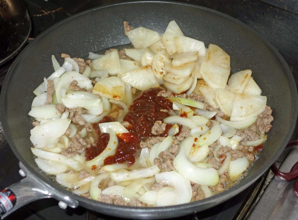 フライパンで炒めたひき肉と大根と玉ねぎと赤い味噌
