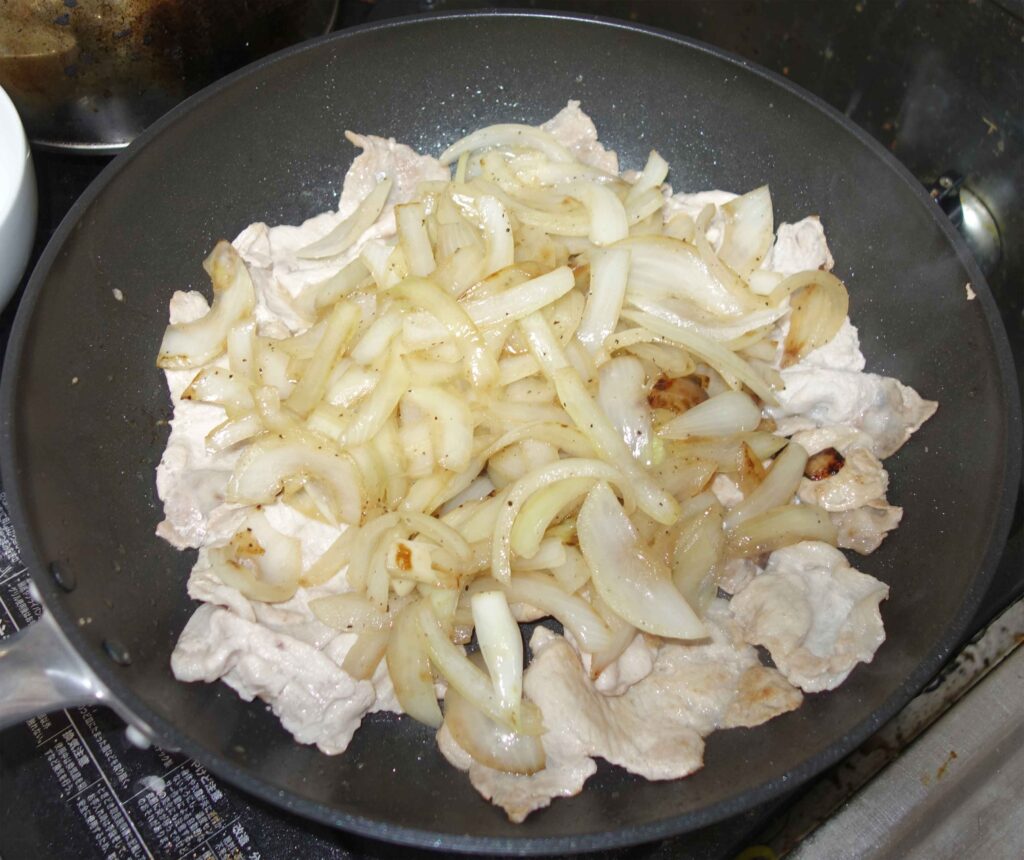 フライパンで豚肉と玉ねぎを炒めている様子