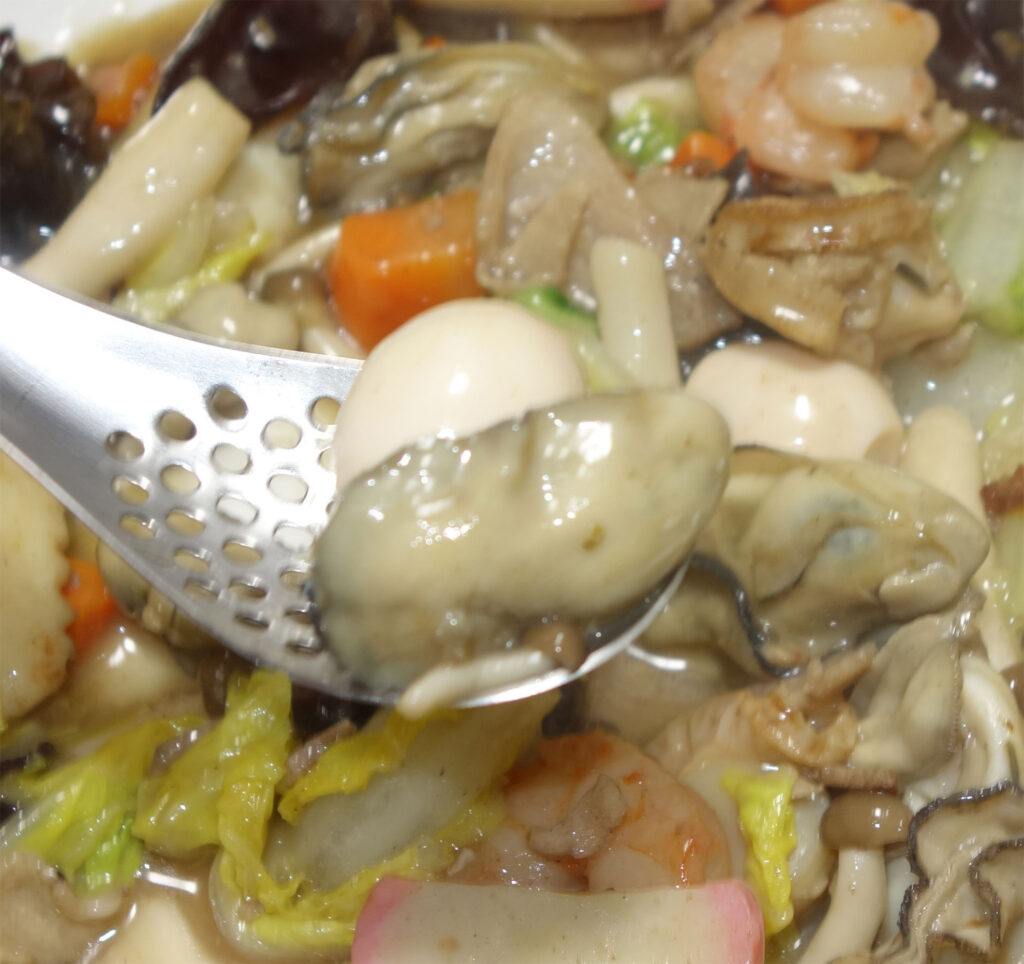 具だくさんの皿うどんをレンゲですくう様子