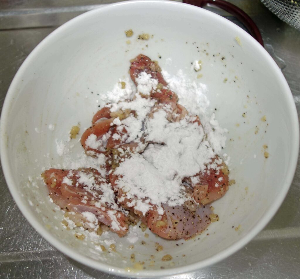 白い器に入った鶏肉に片栗粉をまぶしている様子