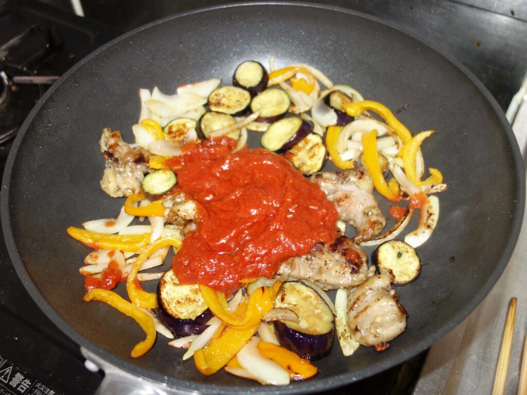フライパンで鶏肉と野菜を炒めトマトソースをかけた料理