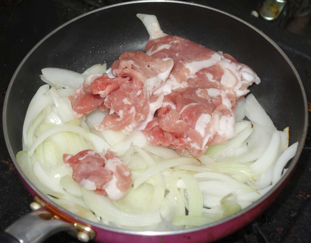 フライパンで豚肉と玉ねぎを炒めている様子