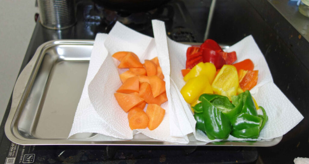 切ったニンジン、赤ピーマン、黄ピーマン、緑ピーマンをペーパータオルに並べた画像