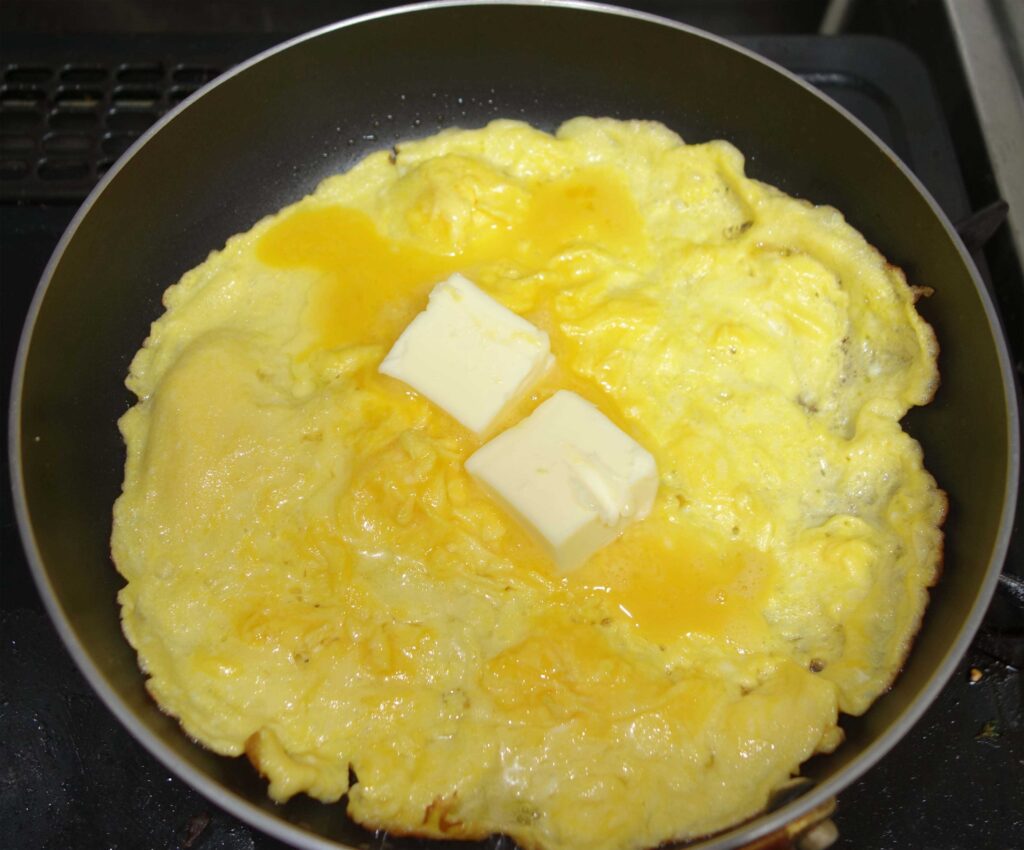 フライパンでバターを溶かしながら焼いている卵焼き