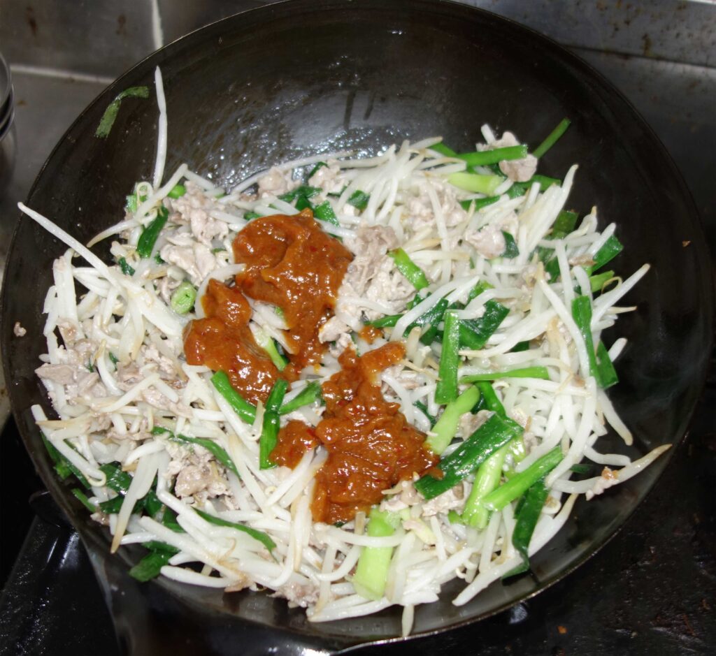 中華鍋で調理中のニラもやし炒め