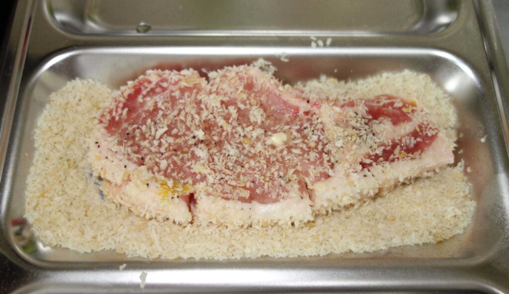 トレーにのったパン粉をつけた豚肉