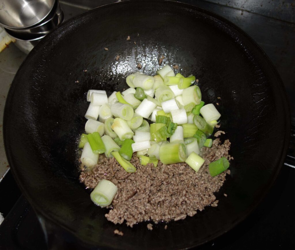 中華鍋で炒めるひき肉とネギ