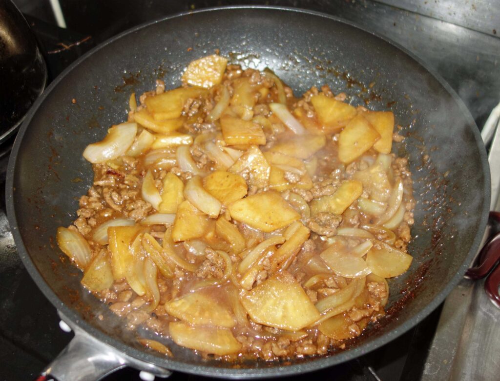 フライパンで炒めたじゃがいもとひき肉と玉ねぎ