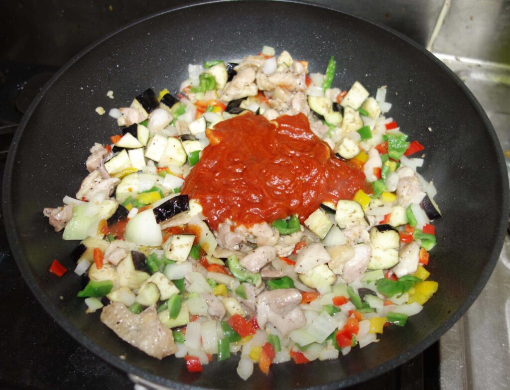 フライパンで鶏肉と野菜を炒めトマトソースをかけた料理