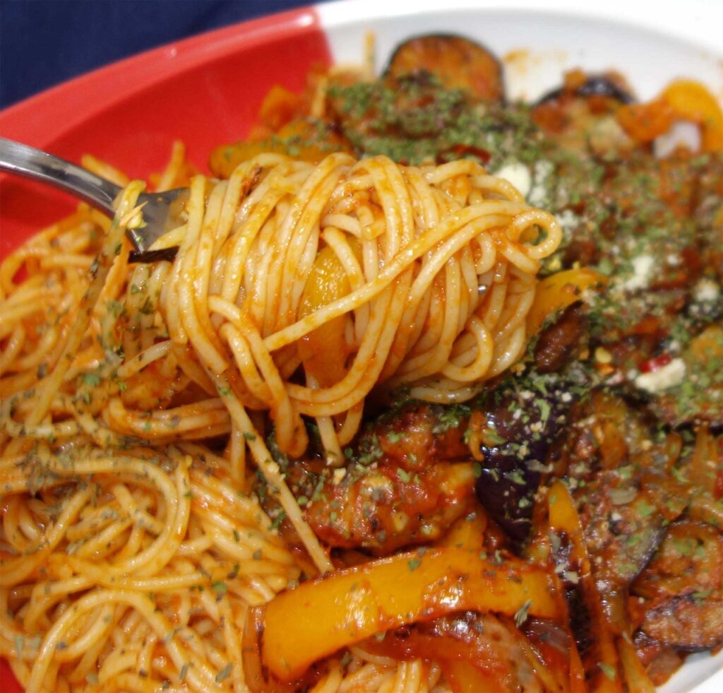 フォークで持ち上げられたナスとピーマンのトマトソーススパゲッティ