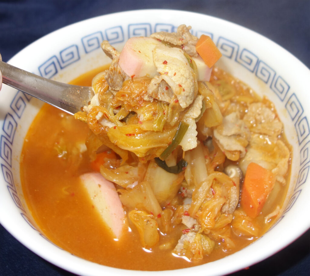 キムチ鍋をスプーンですくう様子
