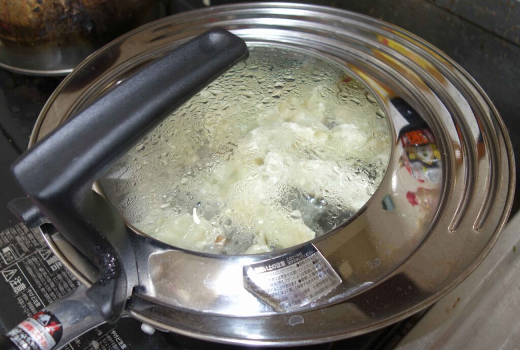 水滴が付いた蓋つきの鍋で調理された餃子