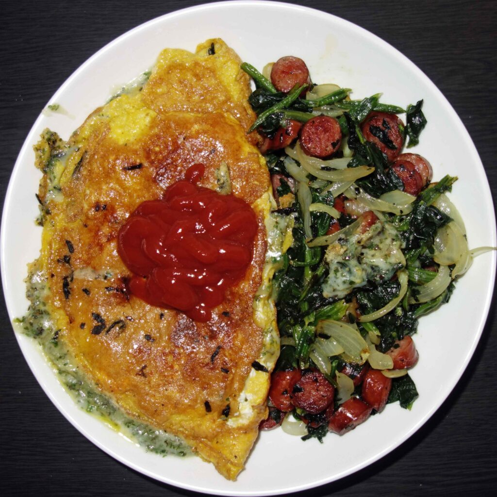 ケチャップがのったオムレツとソーセージとほうれん草の炒め物