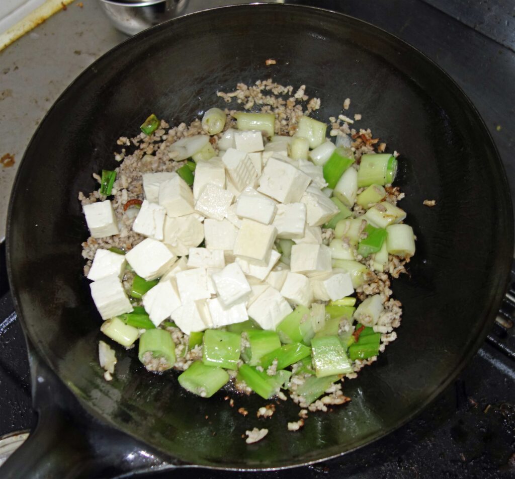 中華鍋で調理中の豆腐とネギとひき肉