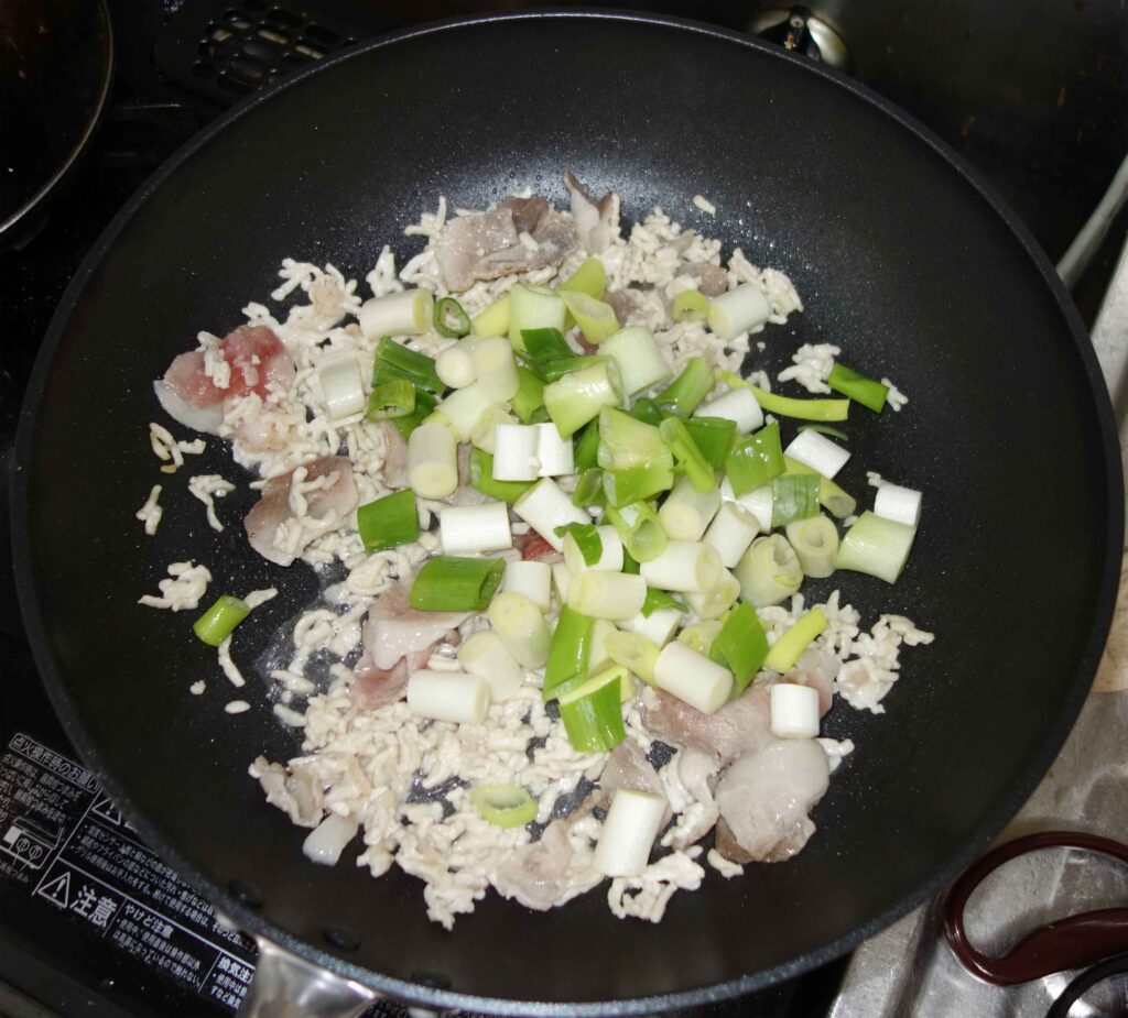 フライパンで調理中の豚肉とご飯とネギ