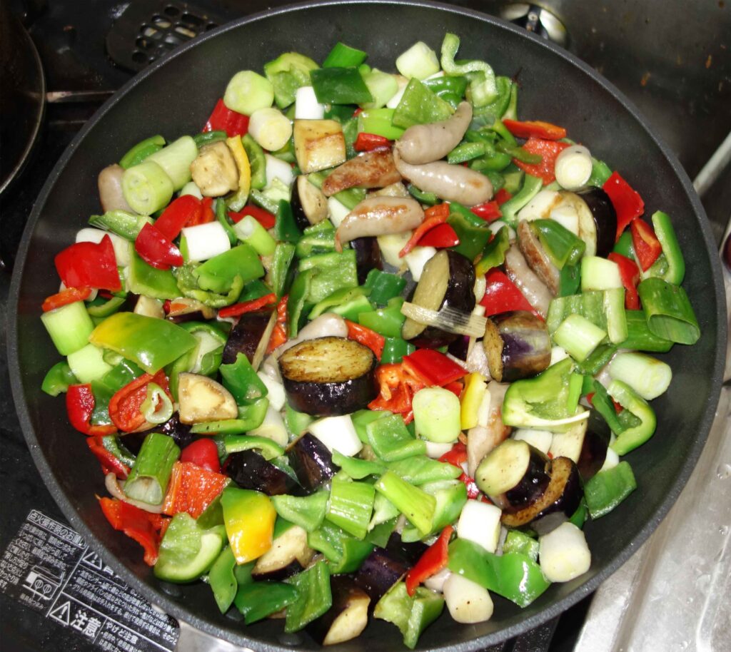 フライパンで調理中の野菜とソーセージ