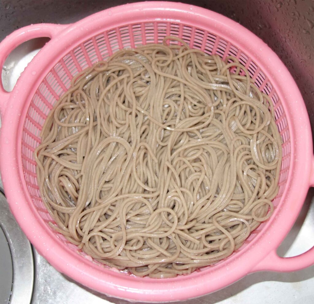 ピンク色のざるに入った蕎麦