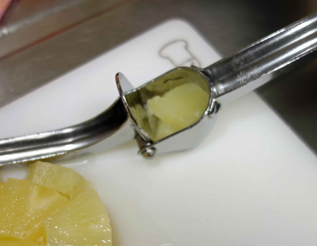 ガーリックプレスでニンニクをつぶす様子